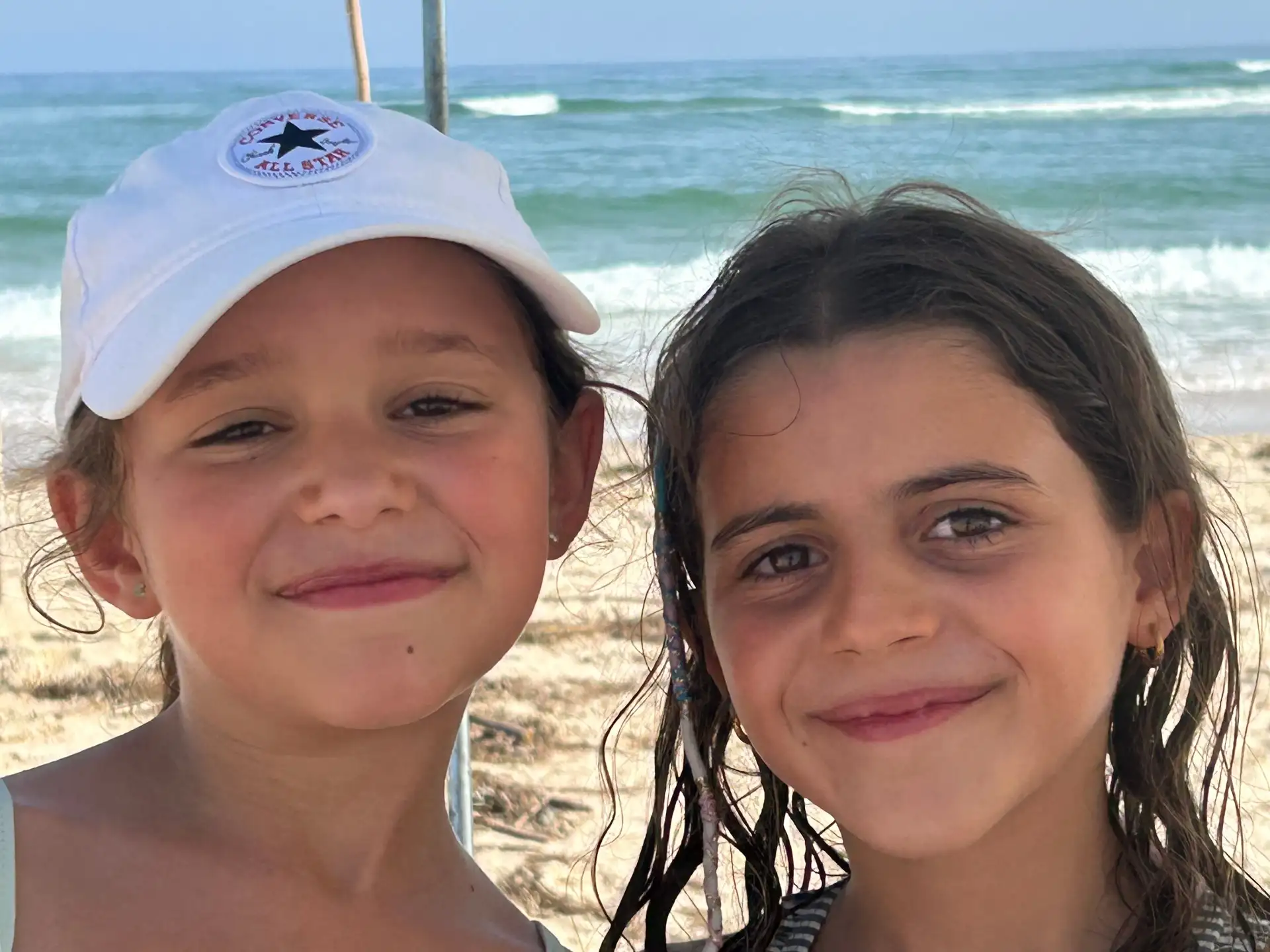 Mimi and Aurora smiling close together, with the sea behind them